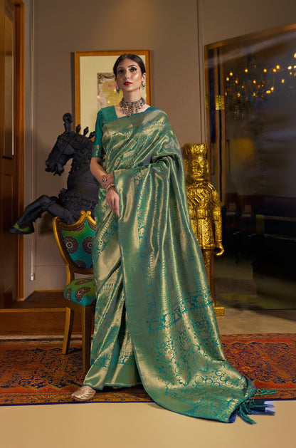 Woman in a green saree standing in an elegant room with decorative elements.