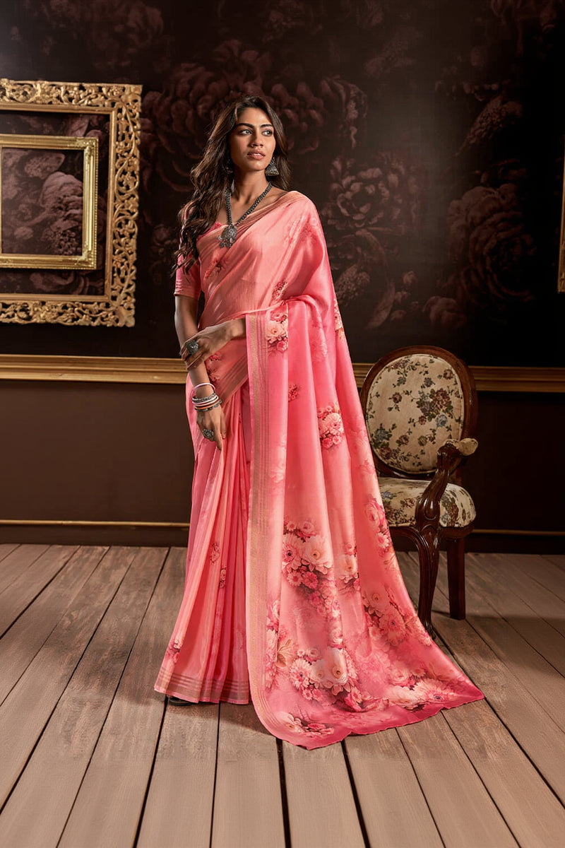 Woman wearing a pink saree with floral patterns in an indoor setting.