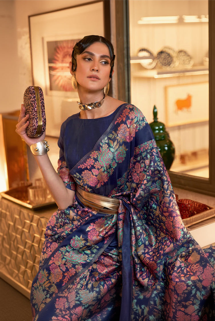 Woman in a floral saree holding a clutch in an indoor setting