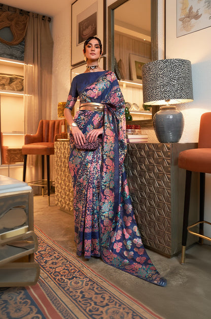 Woman in a floral saree standing in an indoor setting with decorative elements.
