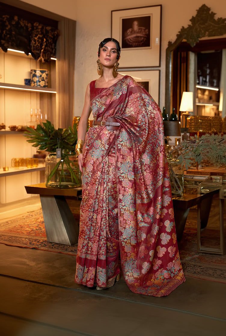Woman wearing a floral saree in an indoor setting with decor elements.