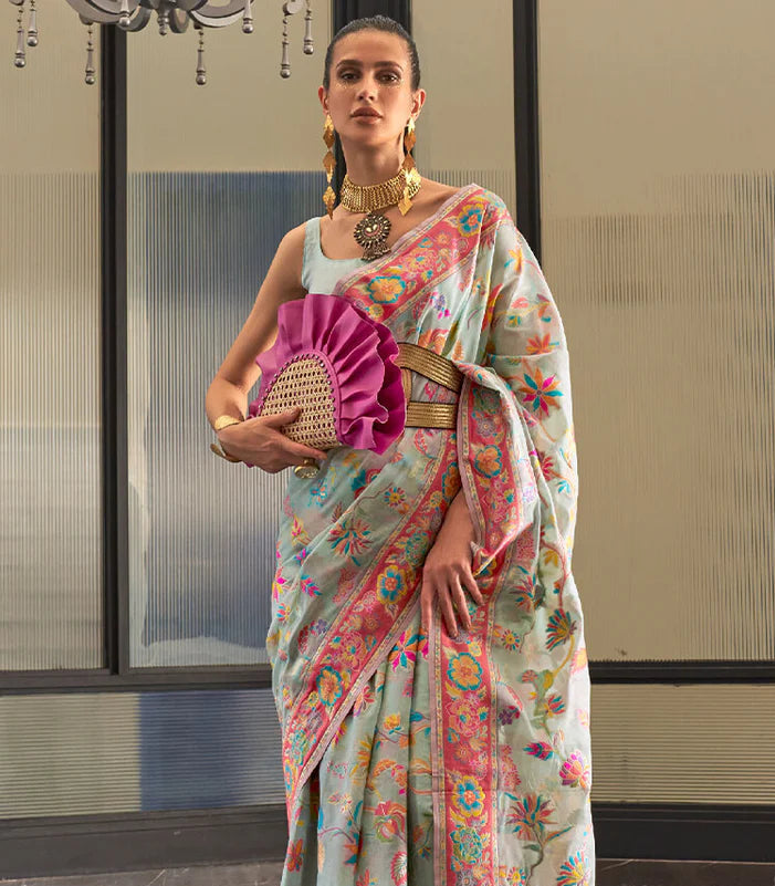 Woman wearing a colorful saree with a pink clutch in an indoor setting