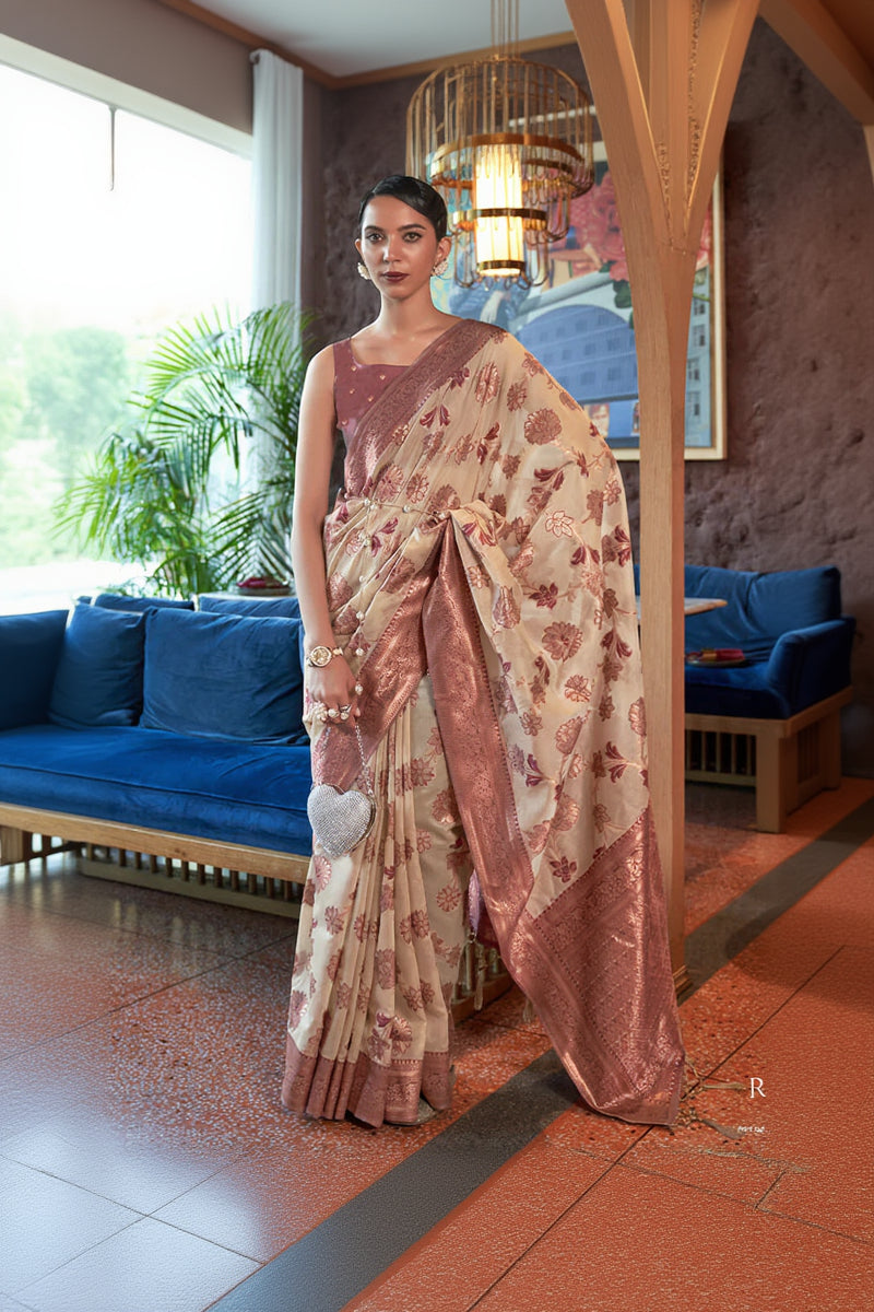 Woman in a floral saree standing in an indoor setting with decor elements.