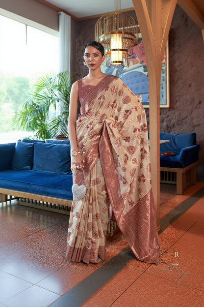 Woman in a floral saree standing in an indoor setting with decor elements.