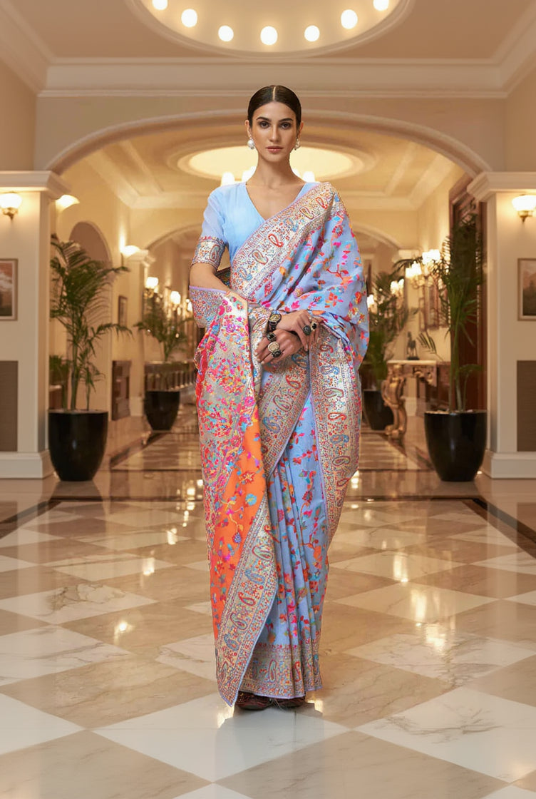 Woman in a colorful saree standing in an elegant hallway.