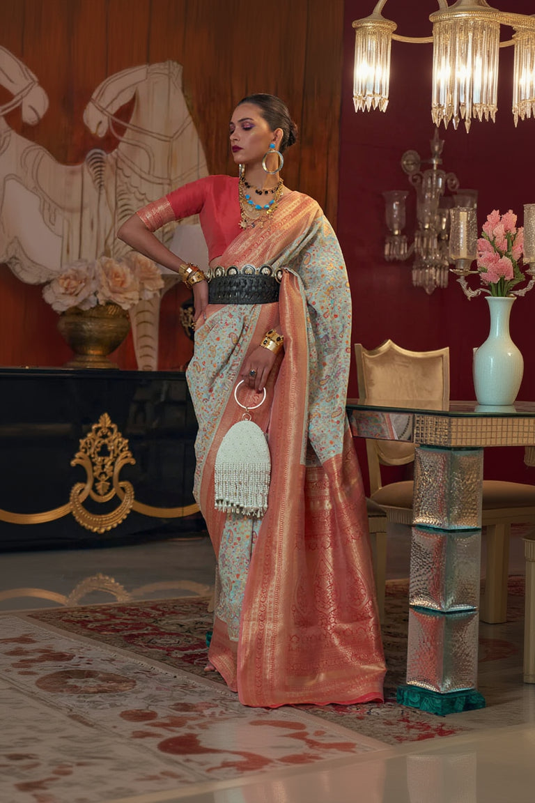Woman in a traditional saree with intricate patterns in a decorated room.