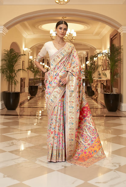Woman in a colorful saree standing in an elegant indoor setting